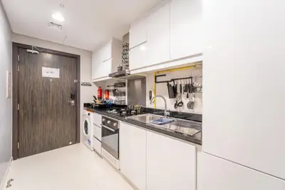 a white kitchen with a sink and a dishwasher at Stylish Studio with Pool View & Free Parking in Dubai