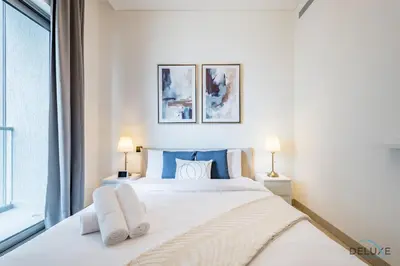 a bedroom with a large white bed with two lamps at Charming 1BR Apartment in Sobha Creek Vistas Reserve, Al Merkadh by Deluxe Holiday Homes in Dubai