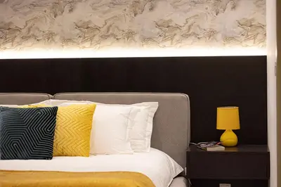 a bed with yellow and white pillows and a painting at 64th Floor Highest Downtown Infinity Pool Burj Khalifa View in Dubai