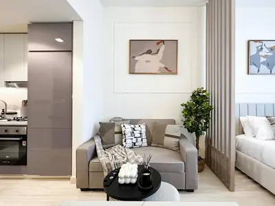 a living room with a couch and a table at Trophy Modern Marvel Cozy Studio with Smart Features in Azizi Riviera in Dubai
