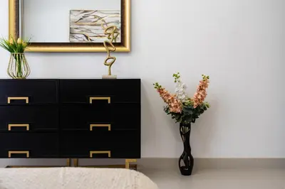 a bedroom with a dresser and a vase with flowers at Dubai Creek - Bright & Beautiful 1BR in The Cove in Dubai