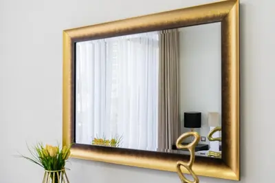 a gold mirror hanging on a wall in a room at Dubai Creek - Bright & Beautiful 1BR in The Cove in Dubai