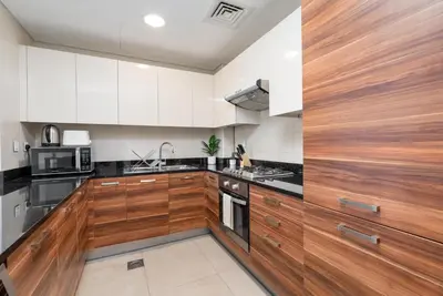a kitchen with white cabinets and black counter tops at Gala Guests - Deluxe Sparkle Residences Dubai Marina in Dubai