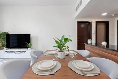 a dining room with a table with chairs and a television at Gala Guests - Deluxe Sparkle Residences Dubai Marina in Dubai