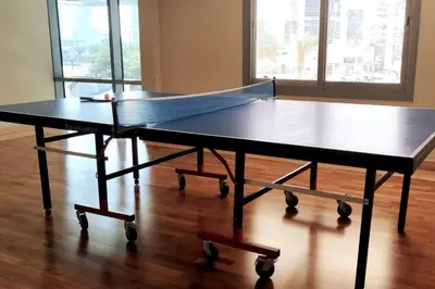 a ping pong table sitting on top of a wooden floor at Skyline & Lake views - Home Cinema - 1-BHK - Prime Location in Dubai