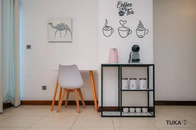 a room with a white chair and a table and a shelf at Skyline & Lake views - Home Cinema - 1-BHK - Prime Location in Dubai
