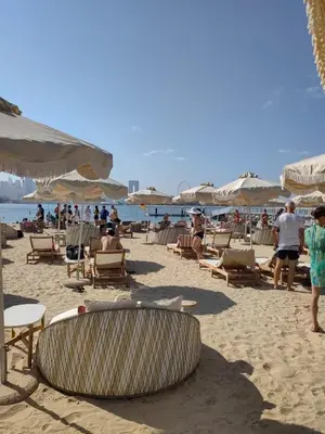 a beach with chairs and umbrellas and people on the sand at 7 palm jumeirah West Beach in Dubai