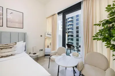 a bedroom with a bed and chairs and a large window at Daniels Poolside Studio in Meydan in Dubai