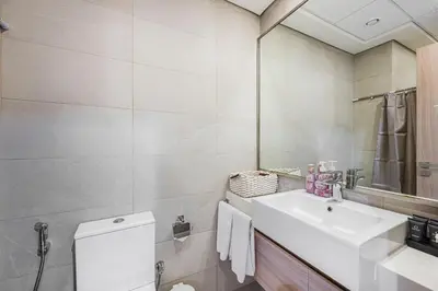 a white bathroom with a sink and a mirror at Daniels Poolside Studio in Meydan in Dubai