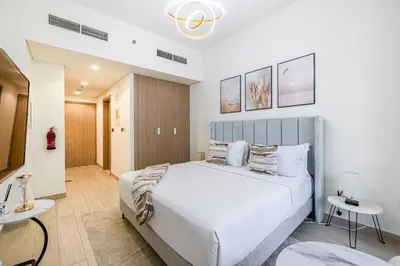 a bedroom with a large white bed and two tables at Daniels Poolside Studio in Meydan in Dubai