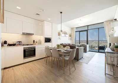 a kitchen and living room with a table and chairs at Palace Residences 2BR with Stunning Creek Views in Dubai