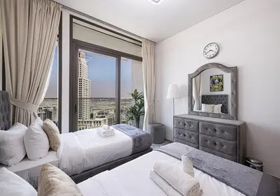 a bedroom with two beds and a large window at Palace Residences 2BR with Stunning Creek Views in Dubai