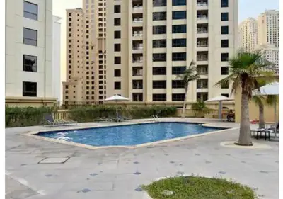 a swimming pool in front of a large building at Aesthetic Beach Apartment , Sleeps 6, Pool, Gym & Waterfront Views in Dubai