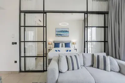 a living room with a couch in front of a bed at Luxury at Socio Dubai Hills, 2 Beds, Sleeps 4 - DVH Holiday Homes in Dubai