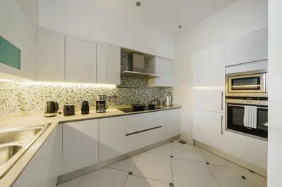 a white kitchen with white cabinets and a sink at Stellar 2BR on Palm Jumeirah - Beach and Pool access in Dubai