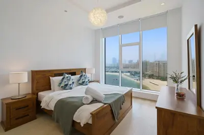 a bedroom with a large bed and a large window at Stellar 2BR on Palm Jumeirah - Beach and Pool access in Dubai