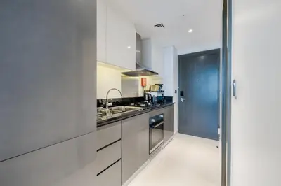 a kitchen with white cabinets and a sink at A Living-Modern Studio Apartment with Balcony & Canal view at Prive 2507B ,Business Bay in Dubai
