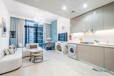 a kitchen and living room with a couch and a table at Charming 1BR Apartment in Azizi Riviera 30, Al Merkadh by Deluxe Holiday Homes in Dubai