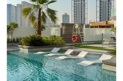 a pool with chairs and a ladder in a city at HAVN - Smart Home Studio in Oxford Terraces, JVC in Dubai
