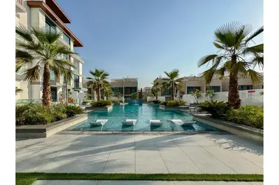 a pool in the middle of a building with palm trees at HAVN - Smart Home Studio in Oxford Terraces, JVC in Dubai