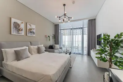 a bedroom with a large bed and a living room at HAVN - Smart Home Studio in Oxford Terraces, JVC in Dubai