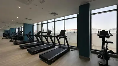 a gym with a row of treadmills and windows at HAVN - 1 Bedroom Unit in Azizi Riviera, Meydan in Dubai