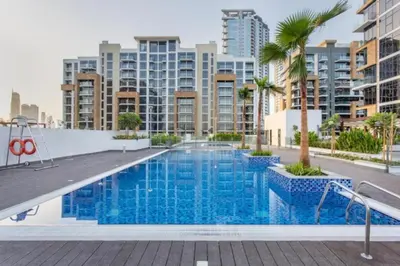a large swimming pool with palm trees and buildings at HAVN - 1 Bedroom Apartment in Azizi Riviera in Dubai