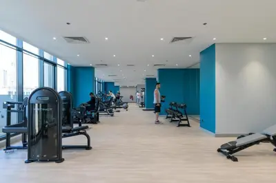 a large room with treadmills and people in a gym at HAVN - 1 Bedroom Apartment in Azizi Riviera in Dubai
