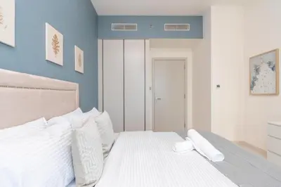 a bedroom with a white bed with blue walls at Sunrise Bay Tower 2 - Beachfront Spectacular Two Bedroom with Private Beach Access in Dubai