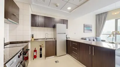 a kitchen with brown cabinets and a white refrigerator at Bay Central - One Bedroom with Marina View in Dubai