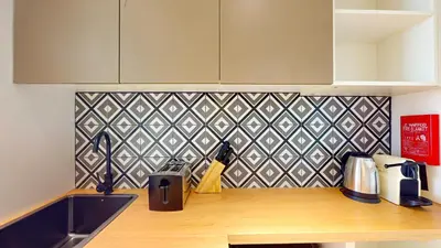 a kitchen with a counter with a sink and a tile wall at The Community Jumeirah Village in Dubai