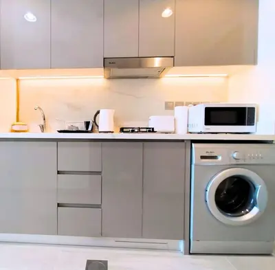 a kitchen with a washing machine and a microwave at Farhad Azizi Residence - Al Jaddaf by Golden Casa in Dubai