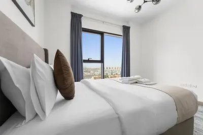 a white bedroom with a large bed with pillows and a window at StoneTree - Newly Furnished - Al Furjan in Dubai