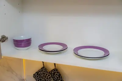 a shelf with three purple and white plates on it at Elite Escape - 1 BHK Getaway in Azizi Riviera in Dubai