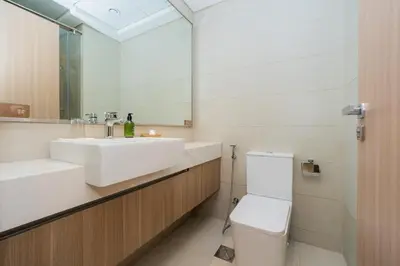 a bathroom with a sink and a toilet and a mirror at Elite Escape - 1 BHK Getaway in Azizi Riviera in Dubai