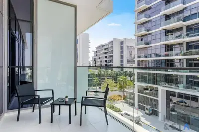 a balcony with two chairs and a table and a large window at Calm and Cozy Studio in Loreto 1A, Damac Hills in Dubai