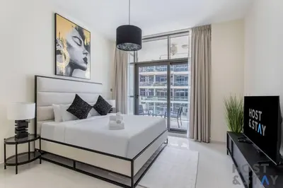 a bedroom with a large white bed and a tv at Calm and Cozy Studio in Loreto 1A, Damac Hills in Dubai