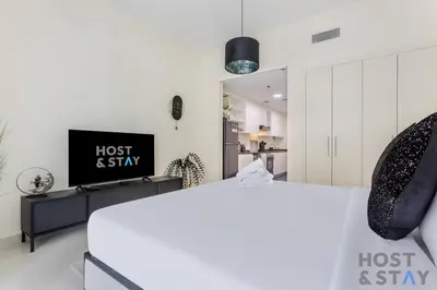 a living room with a bed and a tv at Calm and Cozy Studio in Loreto 1A, Damac Hills in Dubai