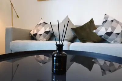 a glass table with a vase on a table with a couch at Luminous 2 BR - Sobha Reserve in Dubai