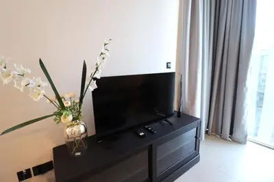 a living room with a tv and flowers in a vase at Luminous 2 BR - Sobha Reserve in Dubai