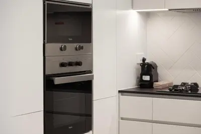 a kitchen with a stove and a microwave at Sophisticated 1BR with Pool View in Belgravia Square JVC in Dubai
