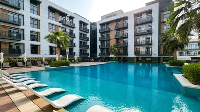 a swimming pool with lounge chairs in front of buildings at Sophisticated 1BR with Pool View in Belgravia Square JVC in Dubai