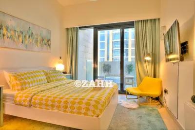 a bedroom with a bed and a yellow chair and a window at Cozy Crib in Dubai