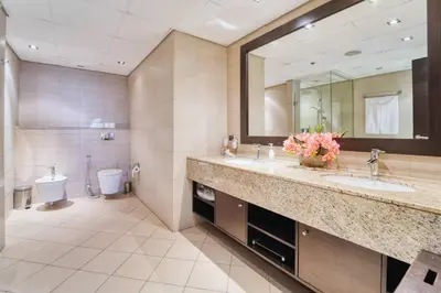 a bathroom with two sinks and a toilet and a mirror at Palm Paradise 1BR - Beachfront Escape with Pool, Gym, Parking & Balcony in Dubai