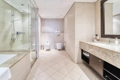 a bathroom with two sinks and a shower and a toilet at Palm Paradise 1BR - Beachfront Escape with Pool, Gym, Parking & Balcony in Dubai