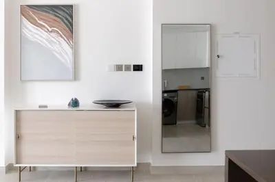 a white kitchen with a counter and a mirror at New building l Near Metro l Spacious lay out in Dubai