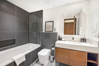 a bathroom with a toilet and a sink and a tub at Daniels 1BR at Creek Edge with Waterfront View in Dubai