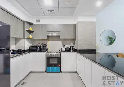 a kitchen with white cabinets and a blue oven at Elegant 1BR Getaway in Bella Rose, Al Barsha in Dubai