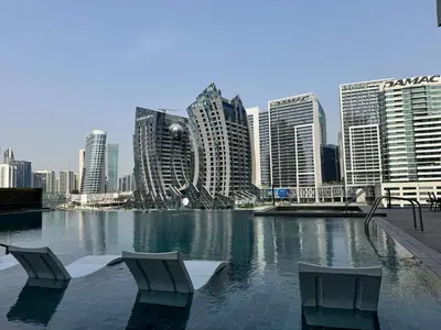 two chairs sitting in a pool in front of a city at 1 Bedroom with Canal View - 15 Northside in Dubai