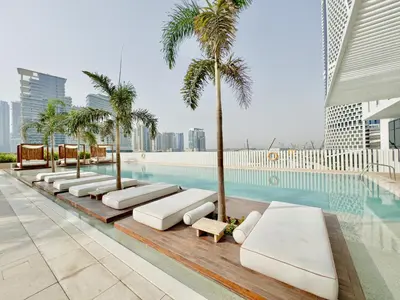 a row of chaise lounge chairs next to a swimming pool at Business-Ready Executive Studio with Burj View in Dubai